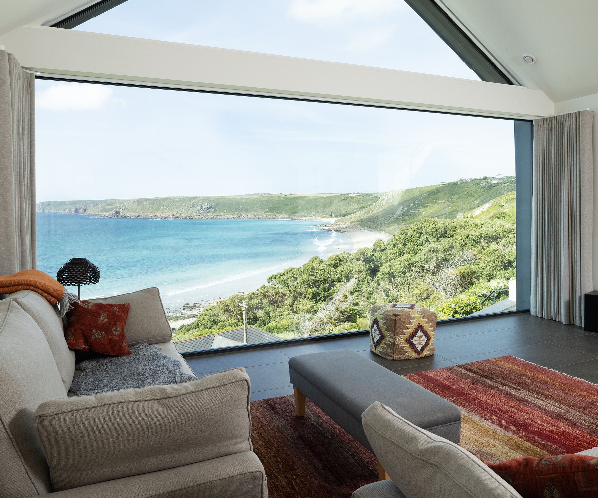 A living room with a large picture window across an entire wall with stunning views across a bay