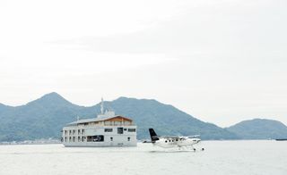 view of Guntû hotel on the water with a sea plane and view of mountains in the background
