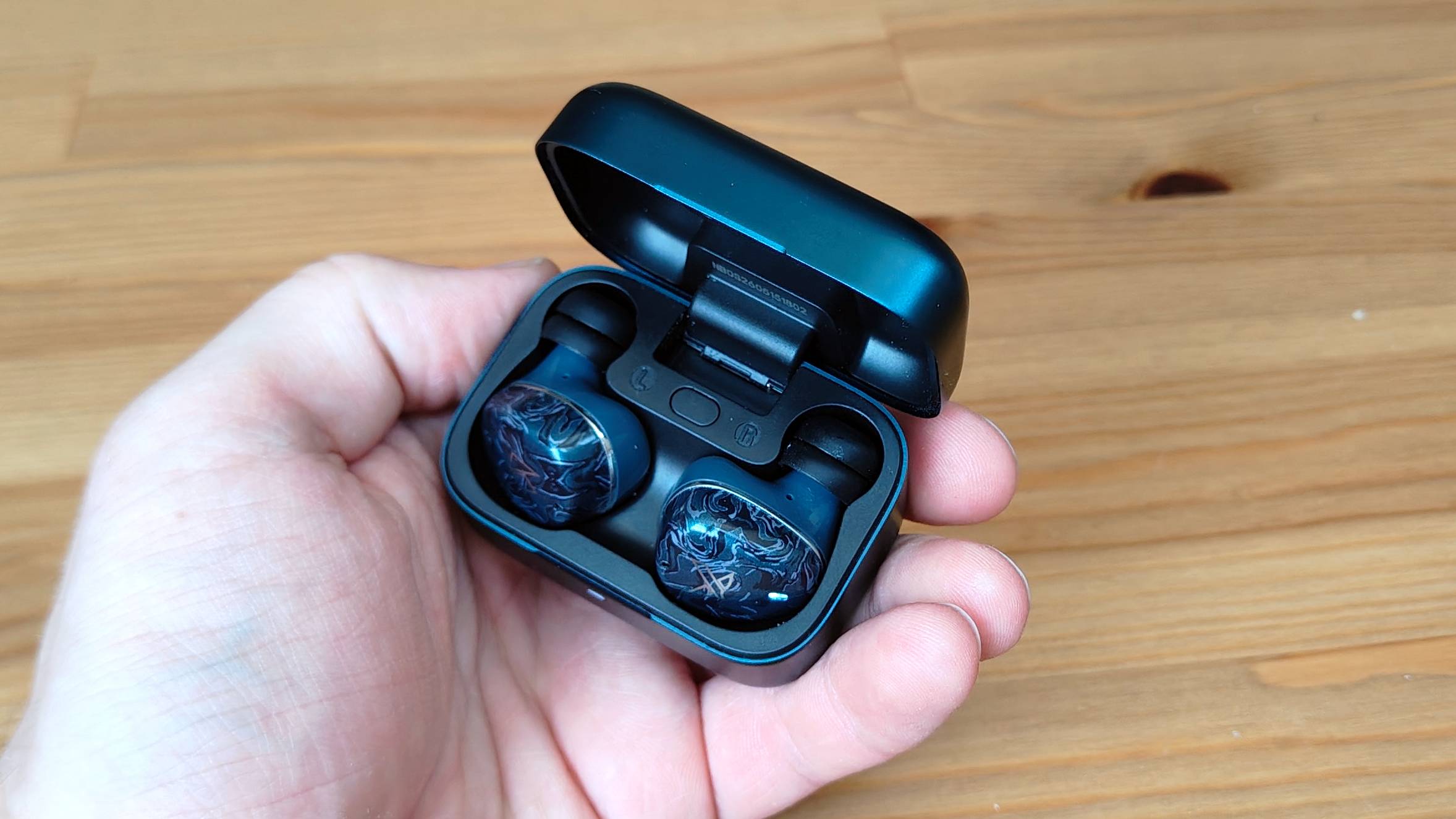 The Noble Osprey earbuds, in their case, in a man's hand.