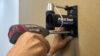 Close up of hands attaching bike stand to wall with screwdriver