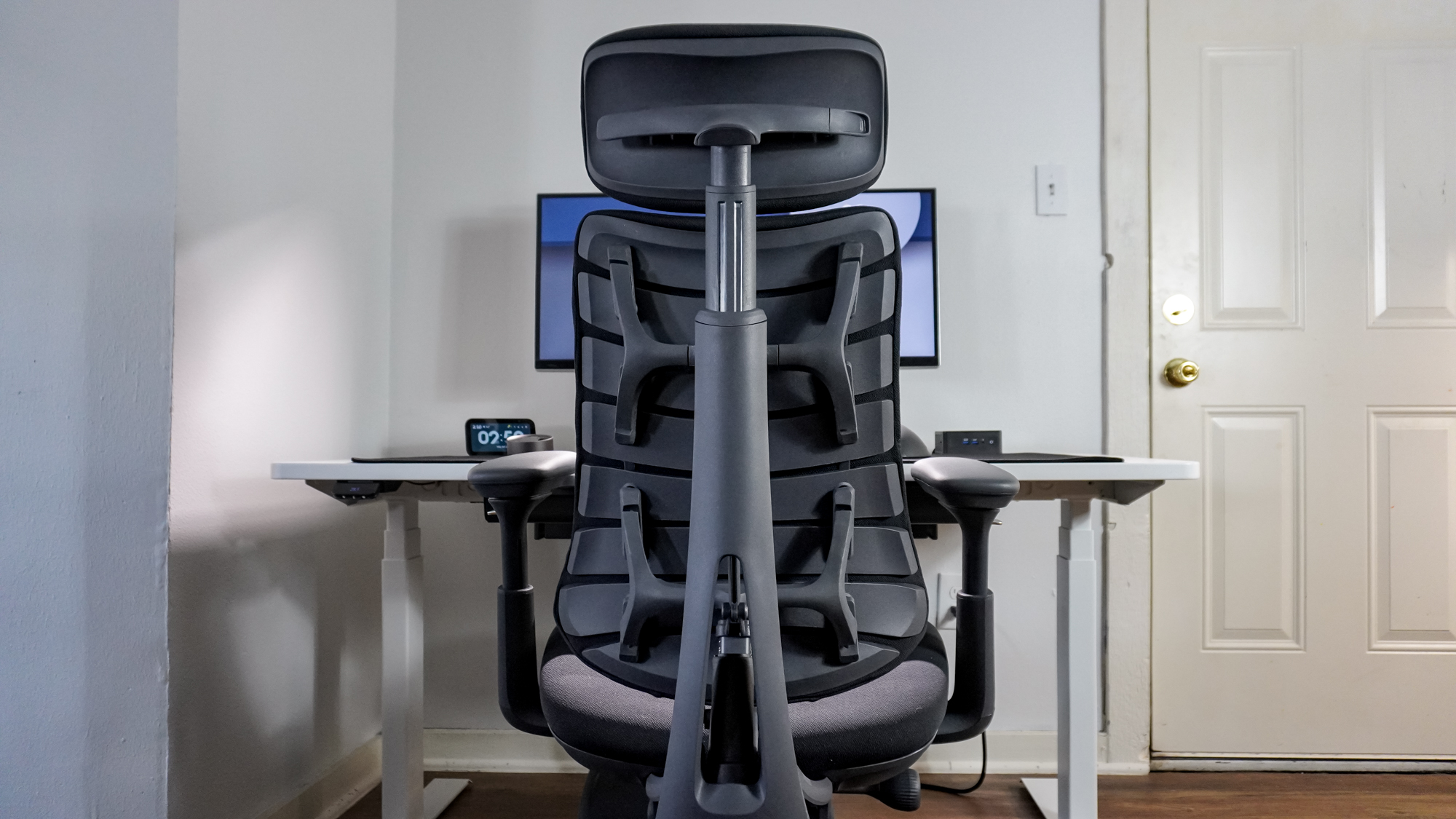 The LiberNovo Omni office chair pushed into a desk and seen from behind with the flexible panels that make up it backrest visible