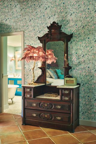vintage dressing table in bedroom with green wallpaper and view of bathroom