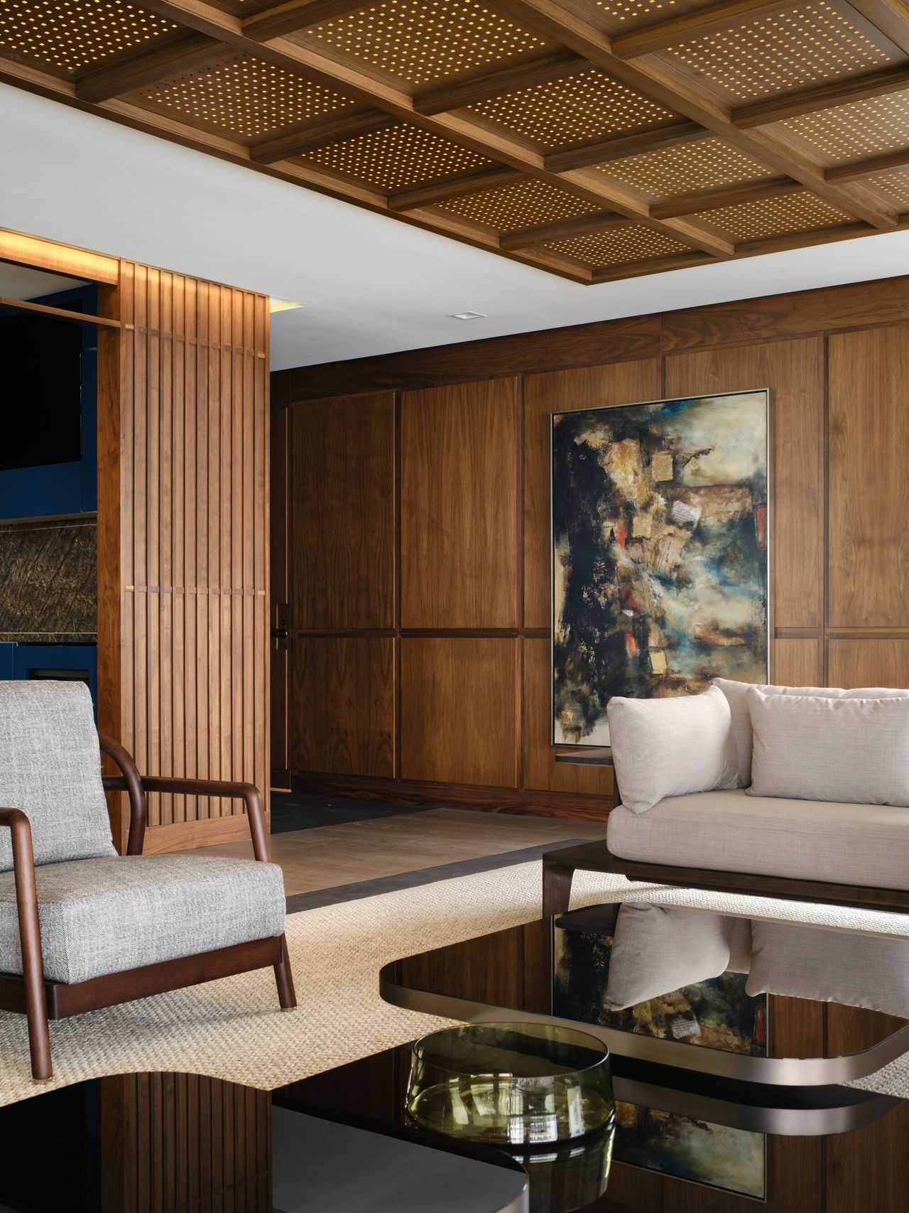 living room with lattice coffered ceiling, timber panelled walls, gray armchair and sofa, black glass coffee table