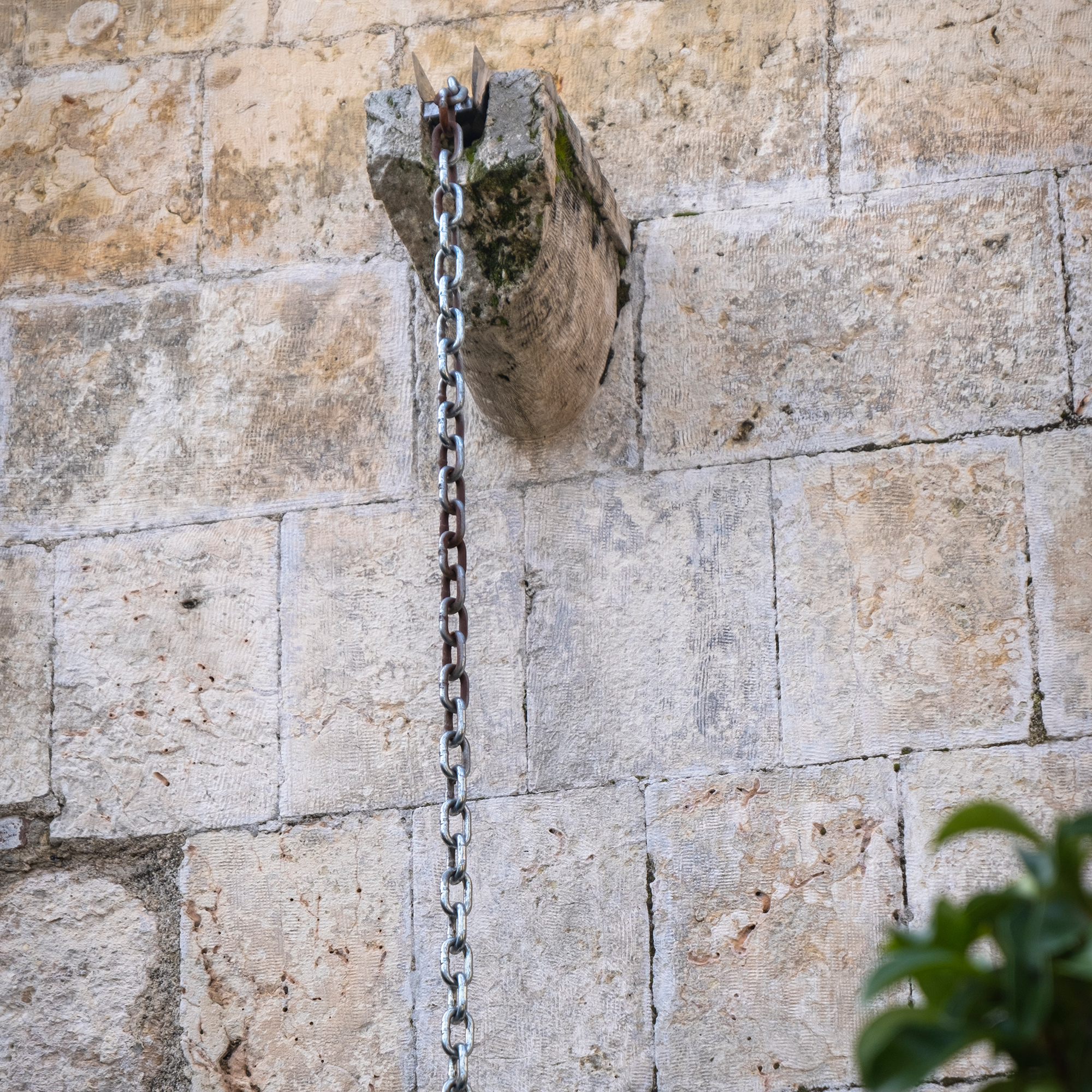 Close up of metal rain chain on stone wall