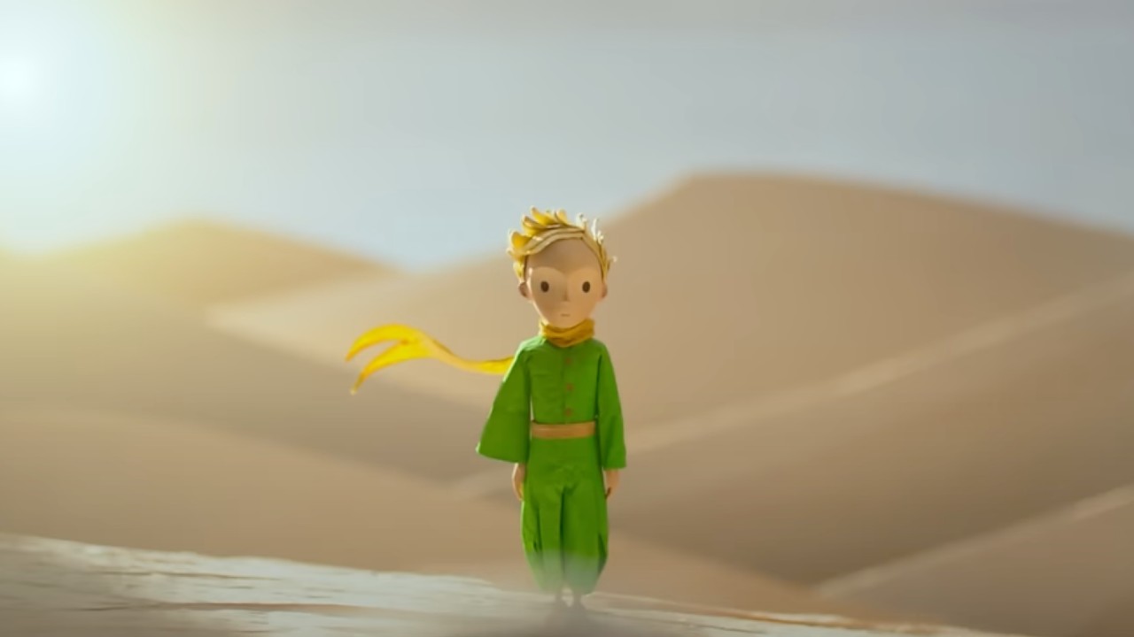 The little prince standing alone in the desert.