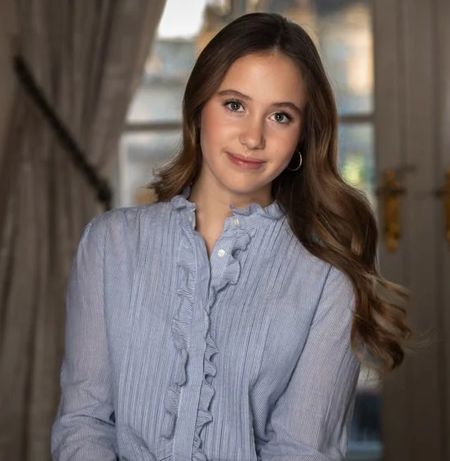 Princess Josephine wearing a blue blouse and posing with her hands on a table