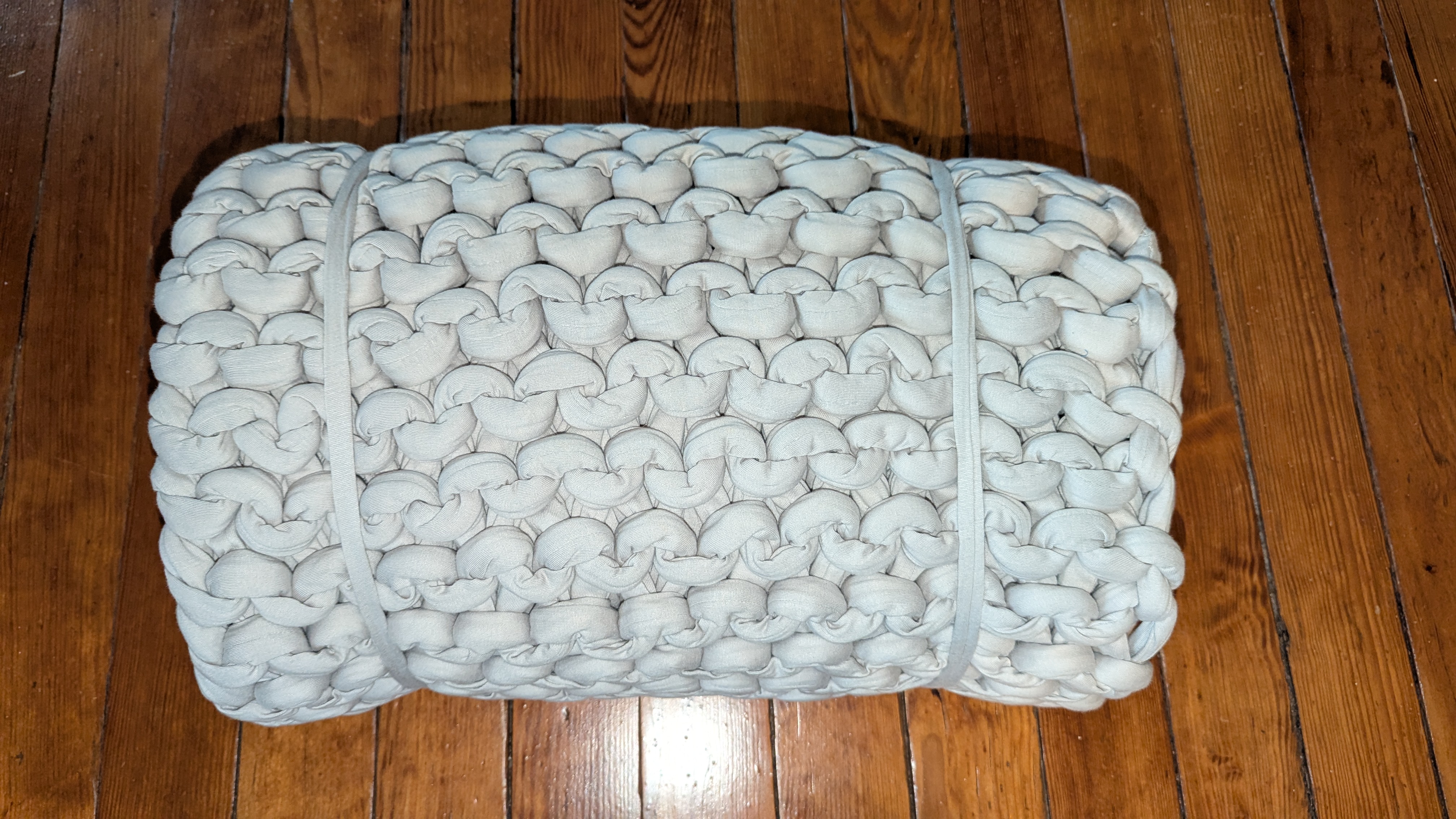 Knitted weighted blanket in grey rolled up