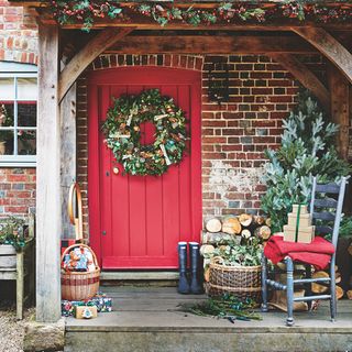 doorway with red door and wreath and bricked wall