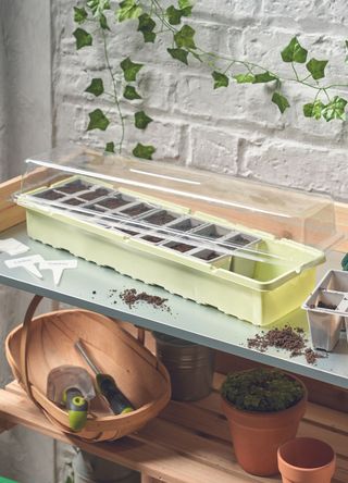 potting table with seedling pots and various gardening tools and terracotta pots