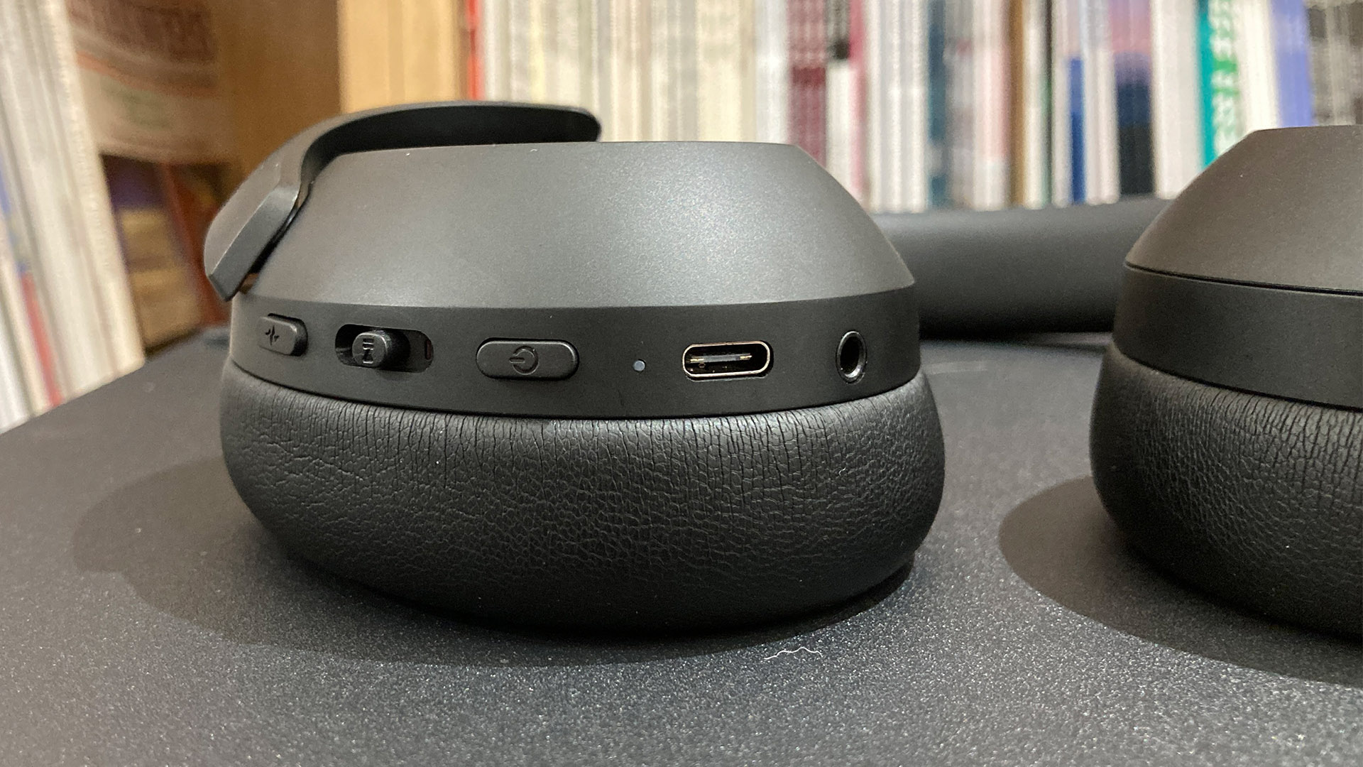 Philips TAH8000E wireless over-ear headphones on black surface detail of one earcup and connections