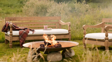 an outdoor sofa and an accent chair in a field with a firepit
