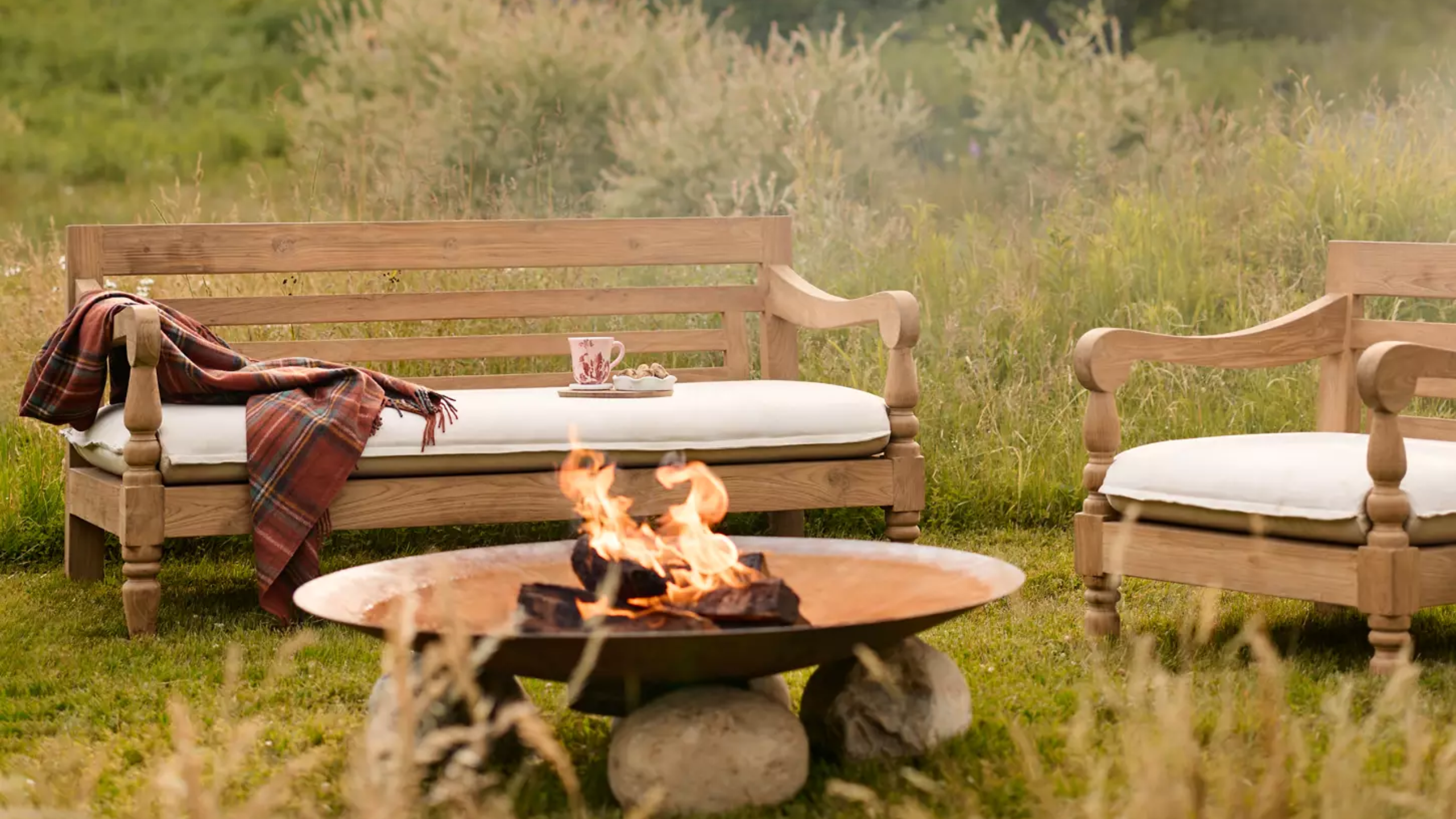 an outdoor sofa and an accent chair in a field with a firepit