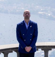 Prince William wearing a blue blazer standing in front of a railing over the sea in Brazil
