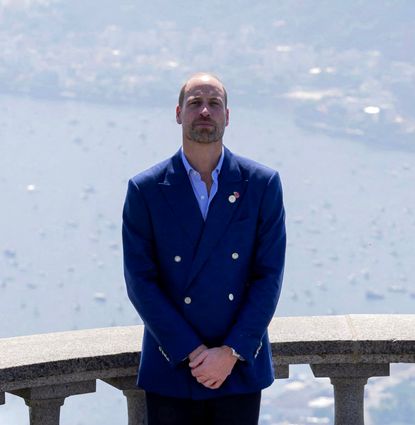Prince William wearing a blue blazer standing in front of a railing over the sea in Brazil