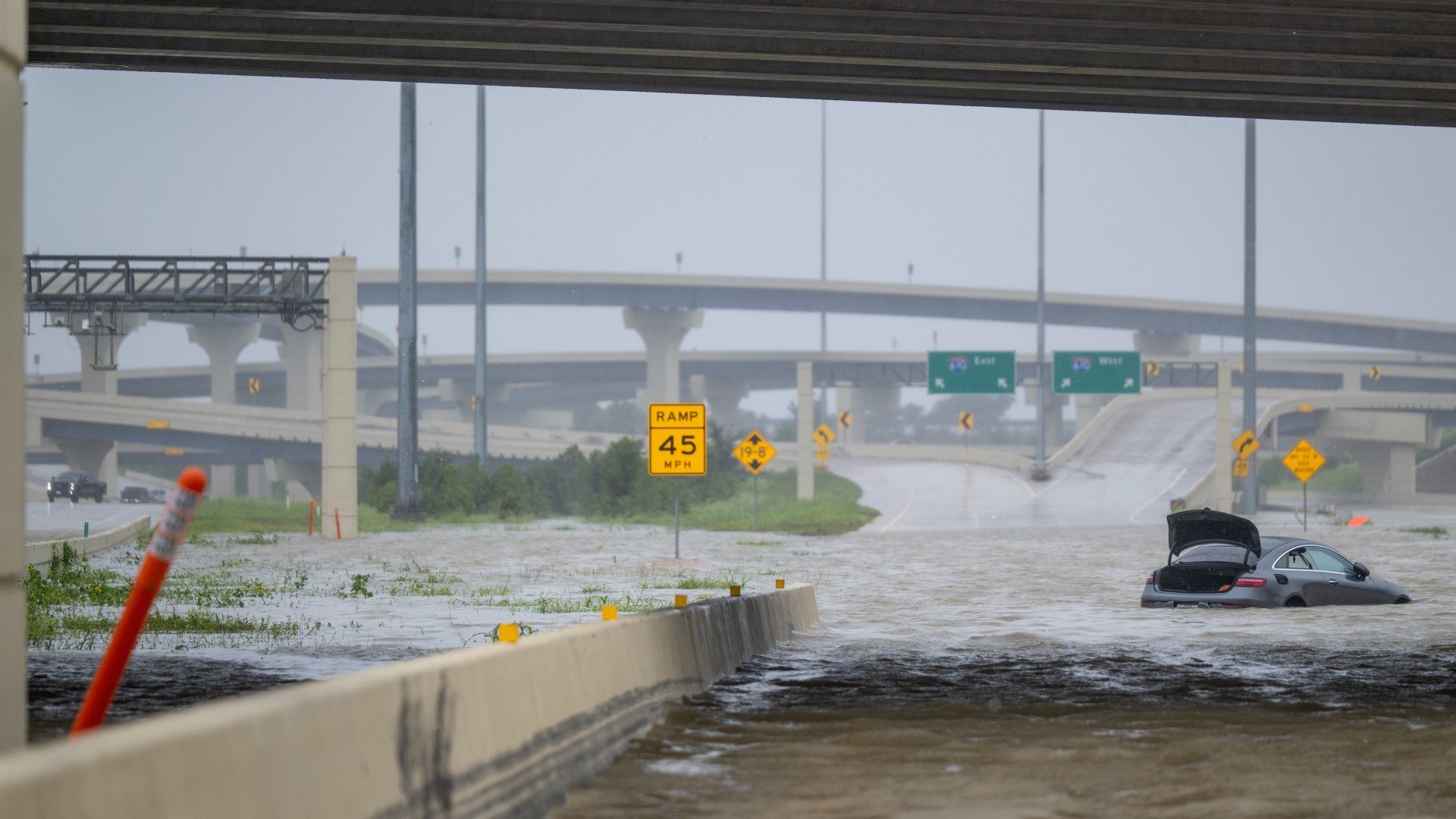 flood waters cover city streets as fallen power lines and damaged buildings can be seen in the background