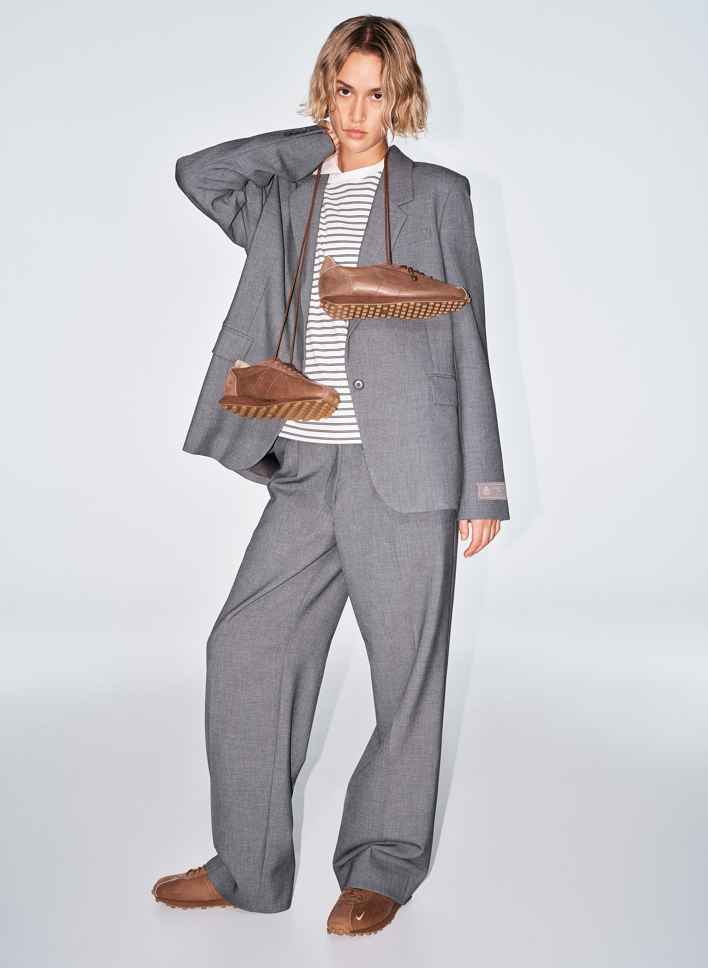 a model wears the aritzia x nike sneakers with a big suit