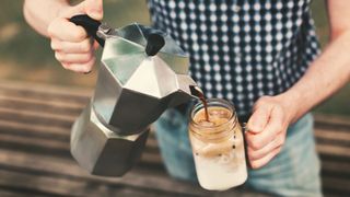 A French press pouring coffee over a kilner jar to make iced coffee