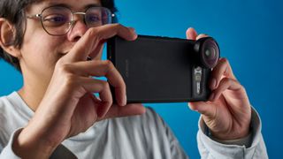 A person holding a Google Pixel 7 Pro with a Moment lens attached