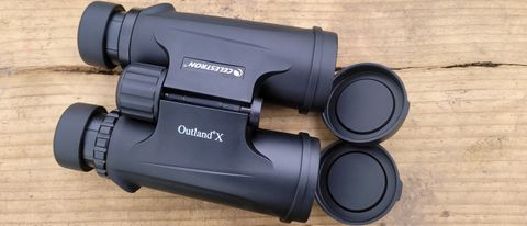A photo of the Celestron Outland X 10x42 binoculars on a wooden platform