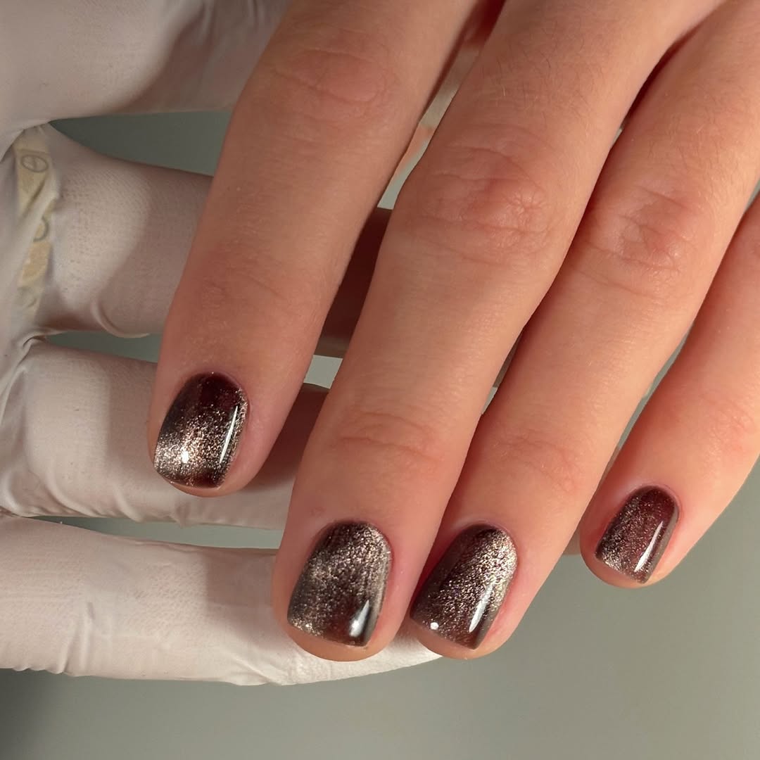 a person wearing a brown cat eye manicure