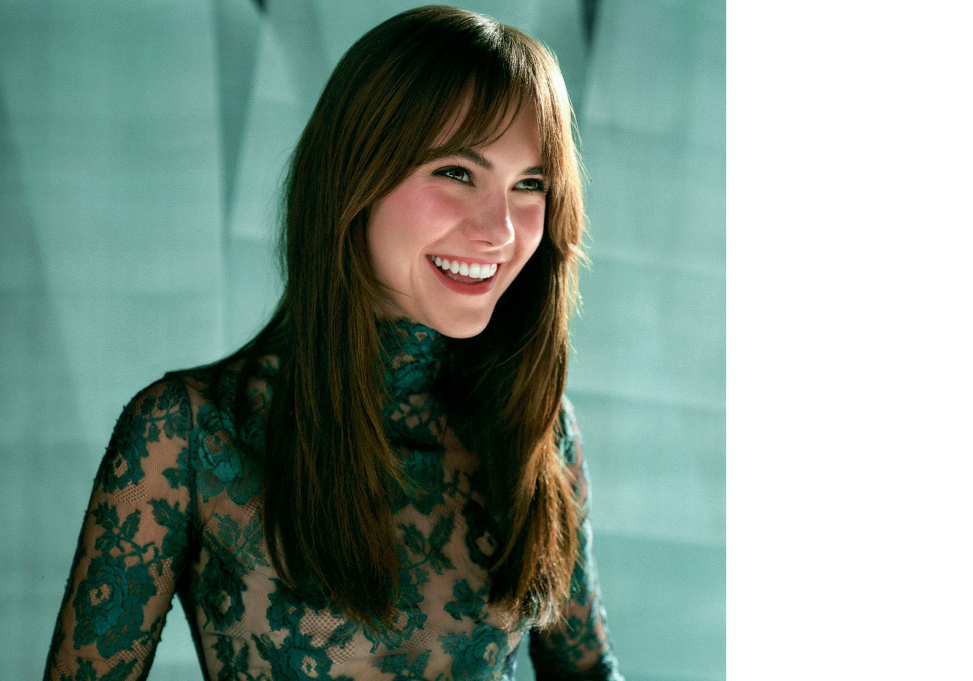 Emilia Jones for WWW's fall Ones to Watch portfolio. She is smiling while looking off camera and wearing a sheer turtleneck top with green lace detailing.