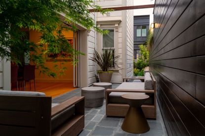 a narrow garden in an alley with outdoor furniture