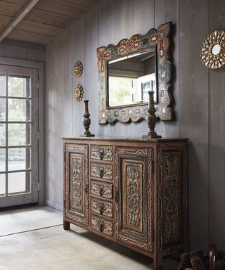 entry foyer with folk art chest and decorative mirror