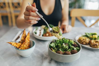 Vegan protein: woman eating a falafel salad