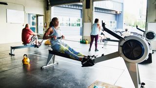 Woman using rowing machine during Crossfit workout at gym