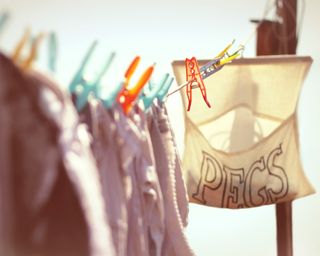 a washing line with colourful clothes pegs and a peg bag - GettyImages-113199221