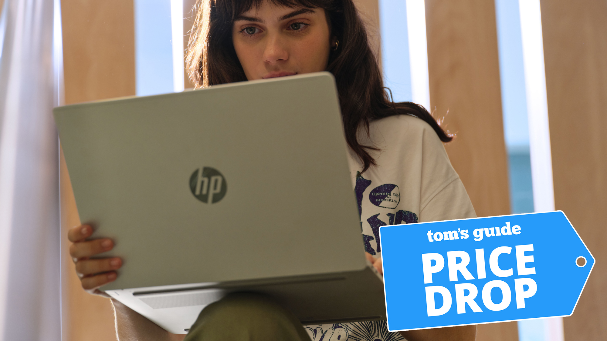 Woman using HP laptop with Price Drop deal badge overlaid