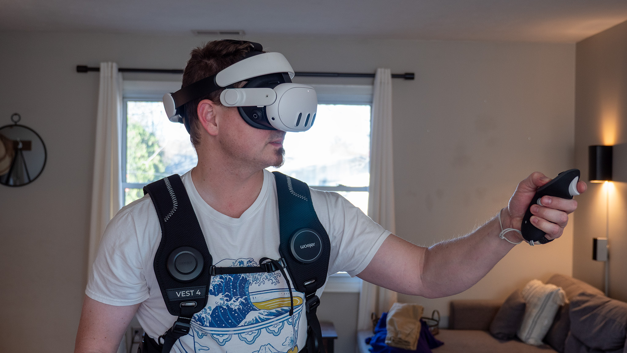 A photo of a man wearing the Meta Quest 3 and the Woojer Haptic Vest 4 from the front, holding up a controller.