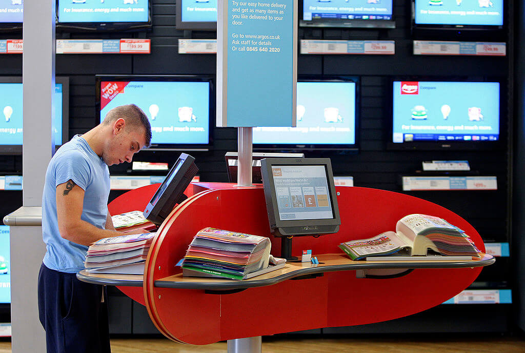 A person shopping inside an Argos using a screen kiosk