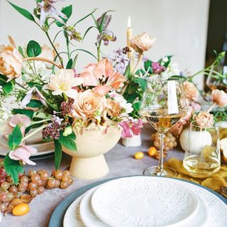 Sophisticated, neutral spring tablescape with burst of pastel salmon and rose, tiered serving plates and wine