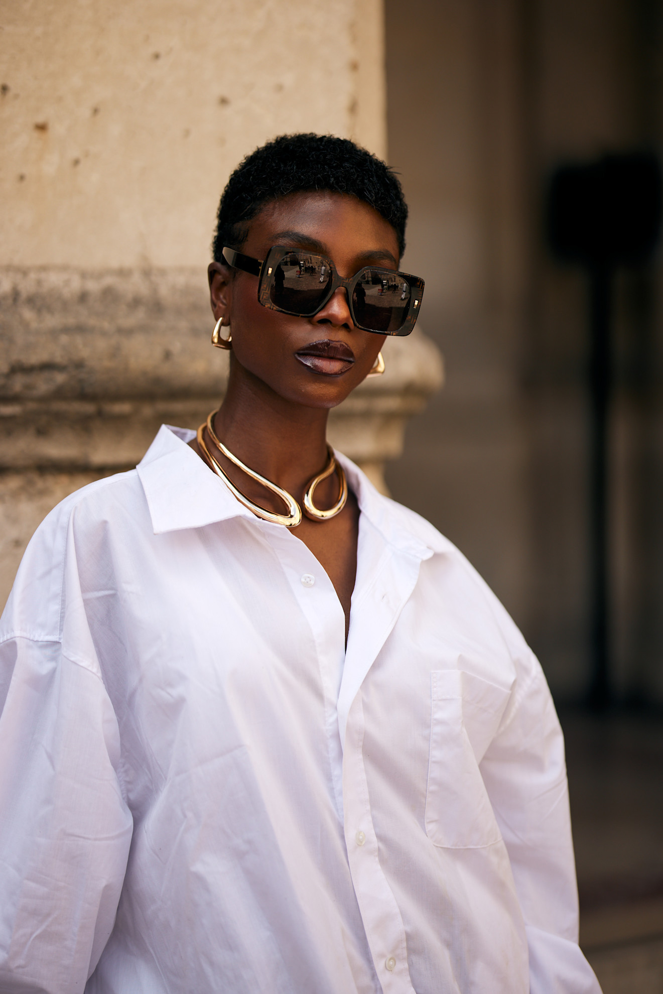 woman wearing a gold necklace and a white button-down in Paris