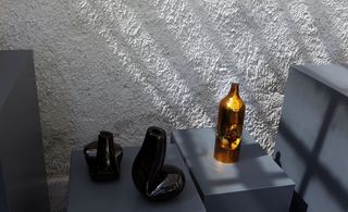 Contemporary shaped vases, photographer on a grey platform next to a wall