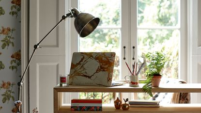 laptop on desk with large lamp and houseplant