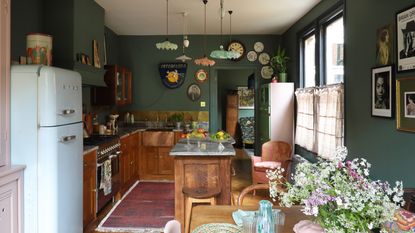 vintage style kitchen diner with dark teal walls, retro fridge, copper sink and mixed glass lampshades