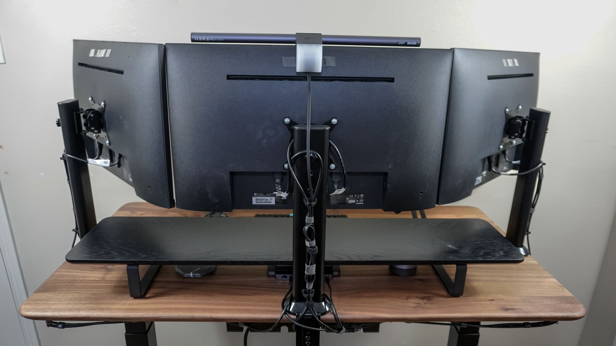A triple monitor setup seen from behind showing off its cable management