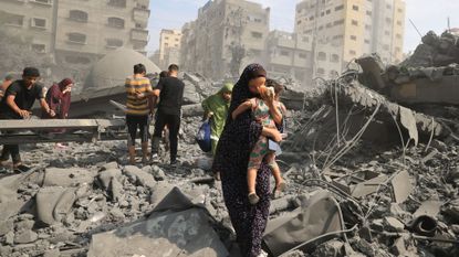Palestinians evacuate the area following an Israeli airstrike on the Sousi mosque in Gaza City on October 9, 2023. Israel continued to battle Hamas fighters on October 9 and massed tens of thousands of troops and heavy armour around the Gaza Strip after vowing a massive blow over the Palestinian militants' surprise attack.