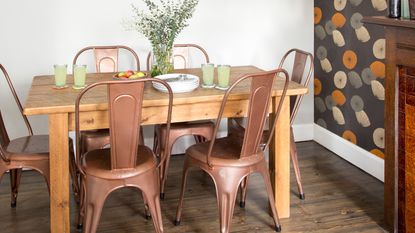 A wooden dining table with a vase of flowers and metal chairs