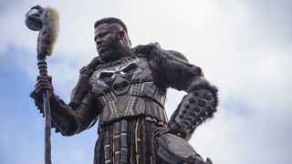 M'Baku looks to his right as he holds his staff and wars his battle armor in Black Panther: Wakanda Forever