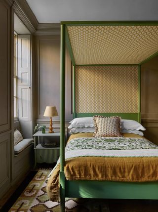 bedroom with printed area rug and green four poster bed, image by Polly Wreford