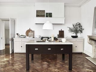 greige kitchen with freestanding black butcher's block with drawers and herringbone flooring