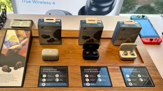 A display of all three Momentum 4 True Wireless earbuds colors in front of their packaging