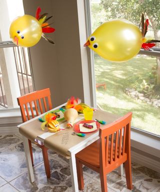 Thanksgiving kids table decor ideas with balloon and gourd turkeys with colorful feathers and googly eyes and kids coloring table runner