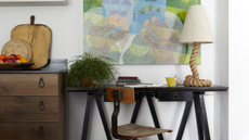 a cool small home office with a green art work above a small black desk with a rope light