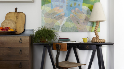 a cool small home office with a green art work above a small black desk with a rope light