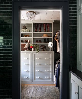 Green tiled walk-in closet with boots, hat and bird ornament