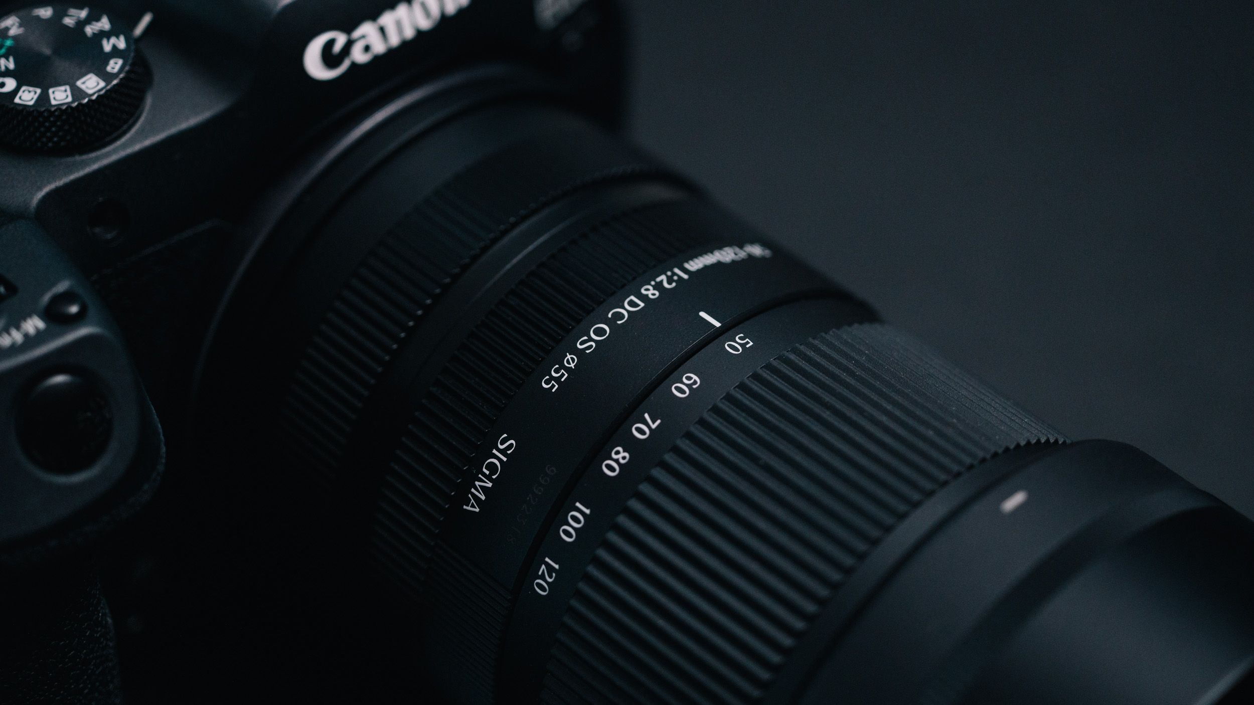 Sigma 50-120mm F2.8 DC OS Contemporary lens attached to a Canon EOS R7, in a lowkey lit studio with dark background